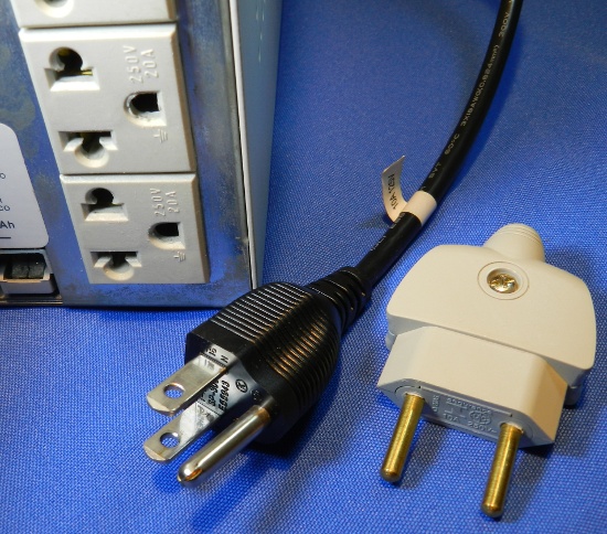 Figura 17 - Plugue NEMA 5 e plugue NBR 2 pinos junto a régua de tomadas universal de um nobreak.