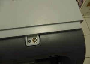 Figura 17 – Parafuso frontal da tampa superior, lado das teclas de comando.