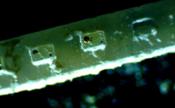 Figura 25 – Aparência de um filamento LED decapado por ácido. É possível perceber ainda os contatos remanescentes sobre as pastilhas LED. Fonte: Electronupdate [56].