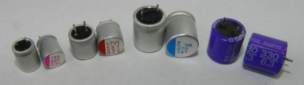 Figura 40 – Capacitores eletrolíticos de polímero condutivo sólido. Da esquerda para a direita: capacitor da FCE, linha RL, de 820uF/6,3V; Fujitsu FPCAP, de 560uF/6,3V; Nippon Chemi-con FPCAP, de 470uF/16V; Sony OS-CON, de 330uF/6,3V. Todos foram identificados pela página japonesa CapacitorWeb [15].