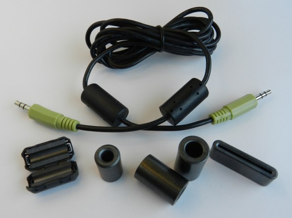 Figura 56 – Ferrites contra interferências de RF. O cabo com plugues P2 estéreo tem dois ferrites moldados nas extremidades, originais. O ferrite abaixo, à esquerda, pode ser montado no cabo pronto, ao contrário dos outros.
