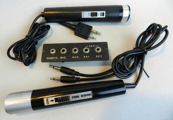 Figura 6 - Microfones com plugues P1 e P2, junto a um painel de conexões de antigo gravador cassete.