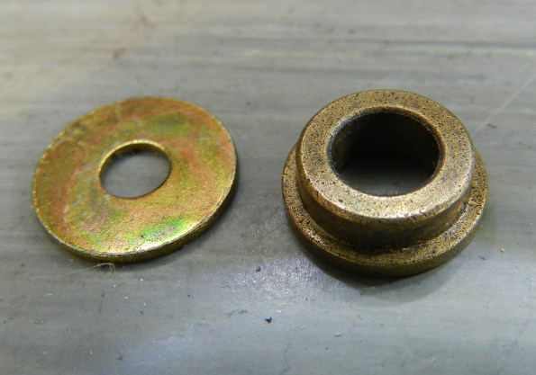 Figura 9 – Detalhe da bucha sinterizada (peça à direita), junto com uma arruela de latão. Observe que a bucha é toda pigmentada, são os poros do material.