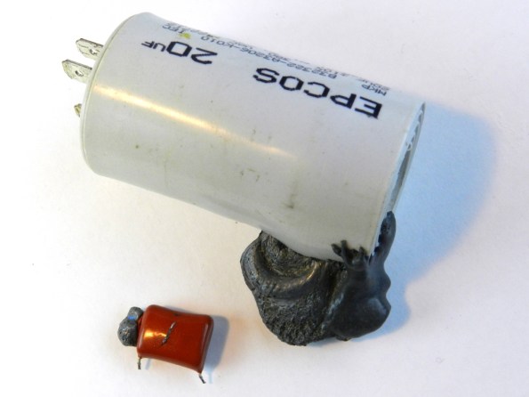 Fig. 9 – Capacitor da figura anterior junto a outro maior, ambos com o mesmo problema (extravasamento de conteúdo). Este último é utilizado em aparelhos de ar condicionado, para dar partida no motor do compressor.