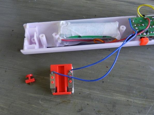 Fig. 13 – Pilha de lítio e circuito de controle, acomodados no cabo da raquete. Observe os frágeis fios azuis que vão do plugue retrátil da rede elétrica à placa.